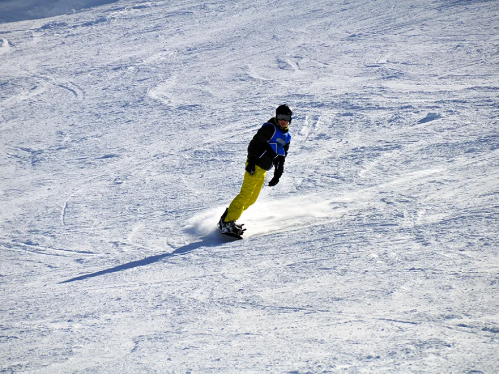Snowboarder in gelber Hose auf der Piste.